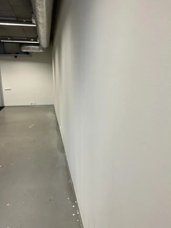 Lange gang met een strak wit afgewerkte wand