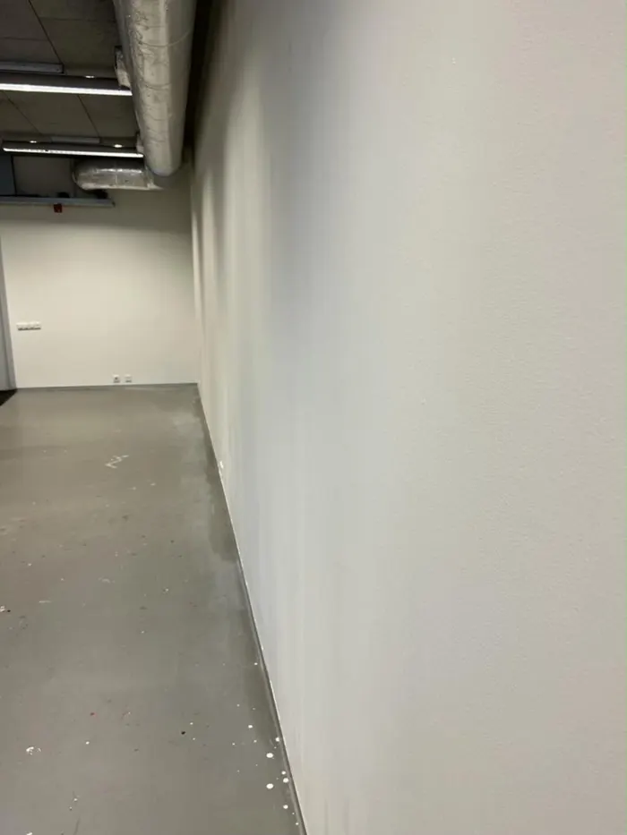 Lange gang met een strak wit afgewerkte wand