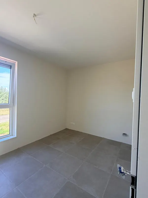 Slaapkamer met raam en strak afgewerkte lichte wanden en plafond